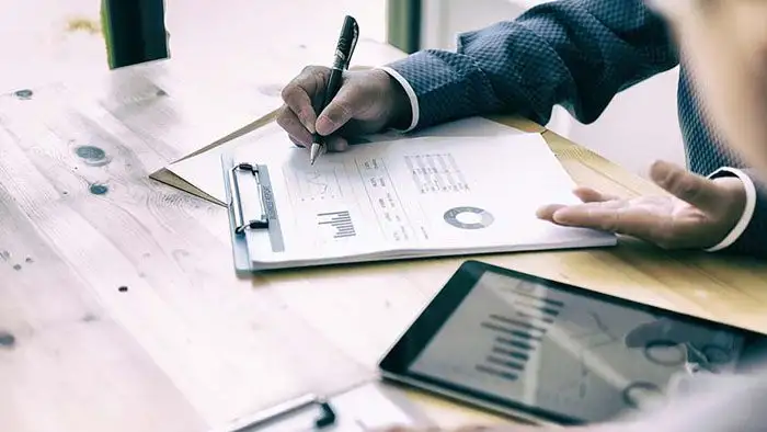 Un asesor revisa un informe financiero con gráficos junto a una tableta